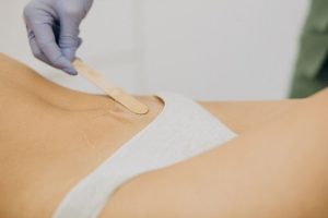 Professional therapist applying warm wax while demonstrating how to wax bikini area safely.